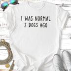 White t-shirt with black text "I WAS NORMAL 2 DOGS AGO".
