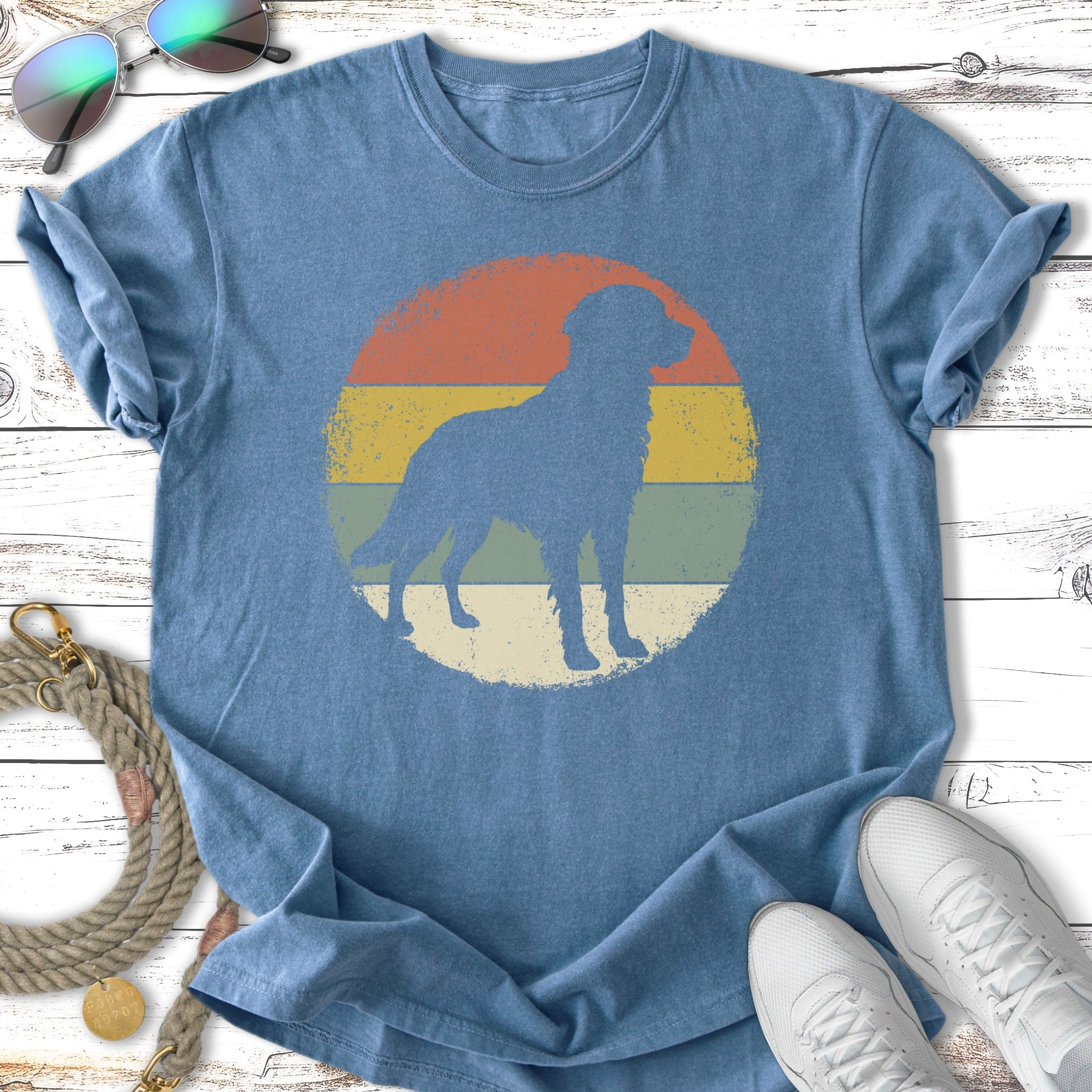 Silhouette of a dog within a distressed circular sunset graphic on a vintage blue t-shirt.
