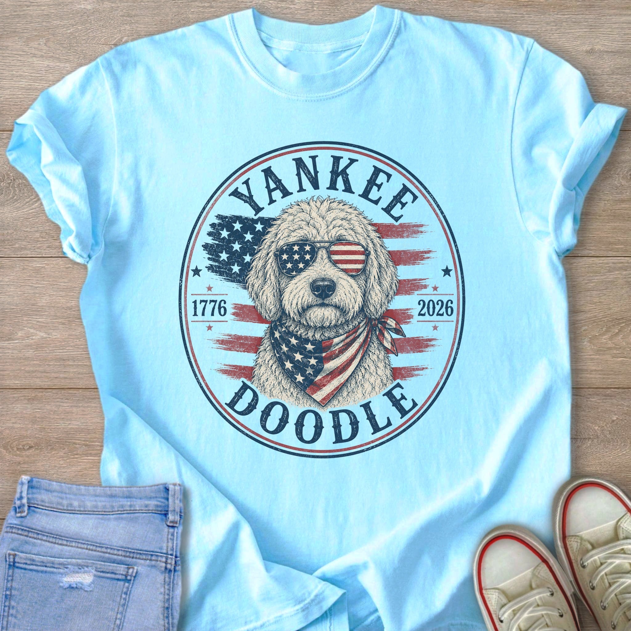 Light blue t-shirt with a round graphic featuring a doodle dog wearing sunglasses and bandana.