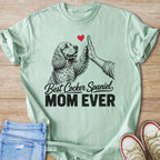 Cocker Spaniel Mom Ever graphic on a light mint t-shirt with a dog high-fiving a hand.