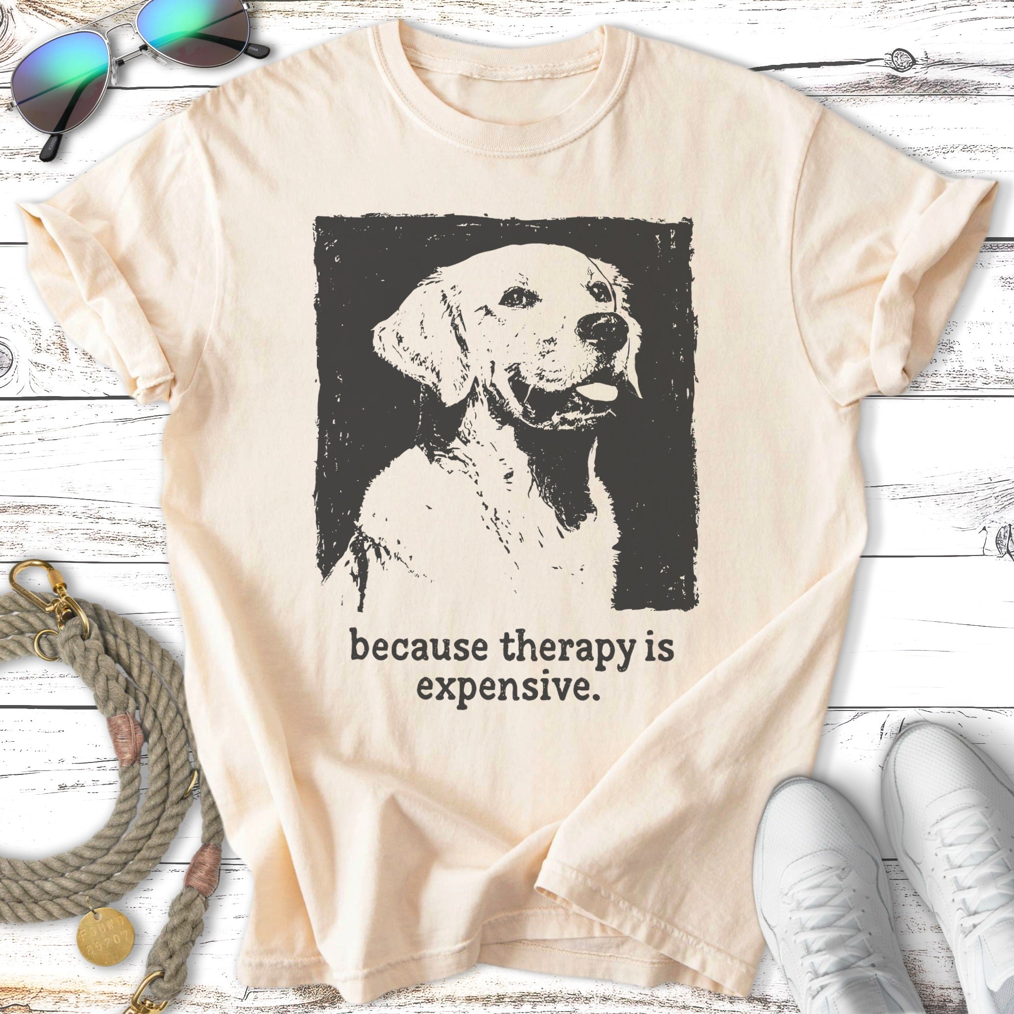 Cream t-shirt with black ink sketch of a golden retriever and text "Because therapy is expensive."