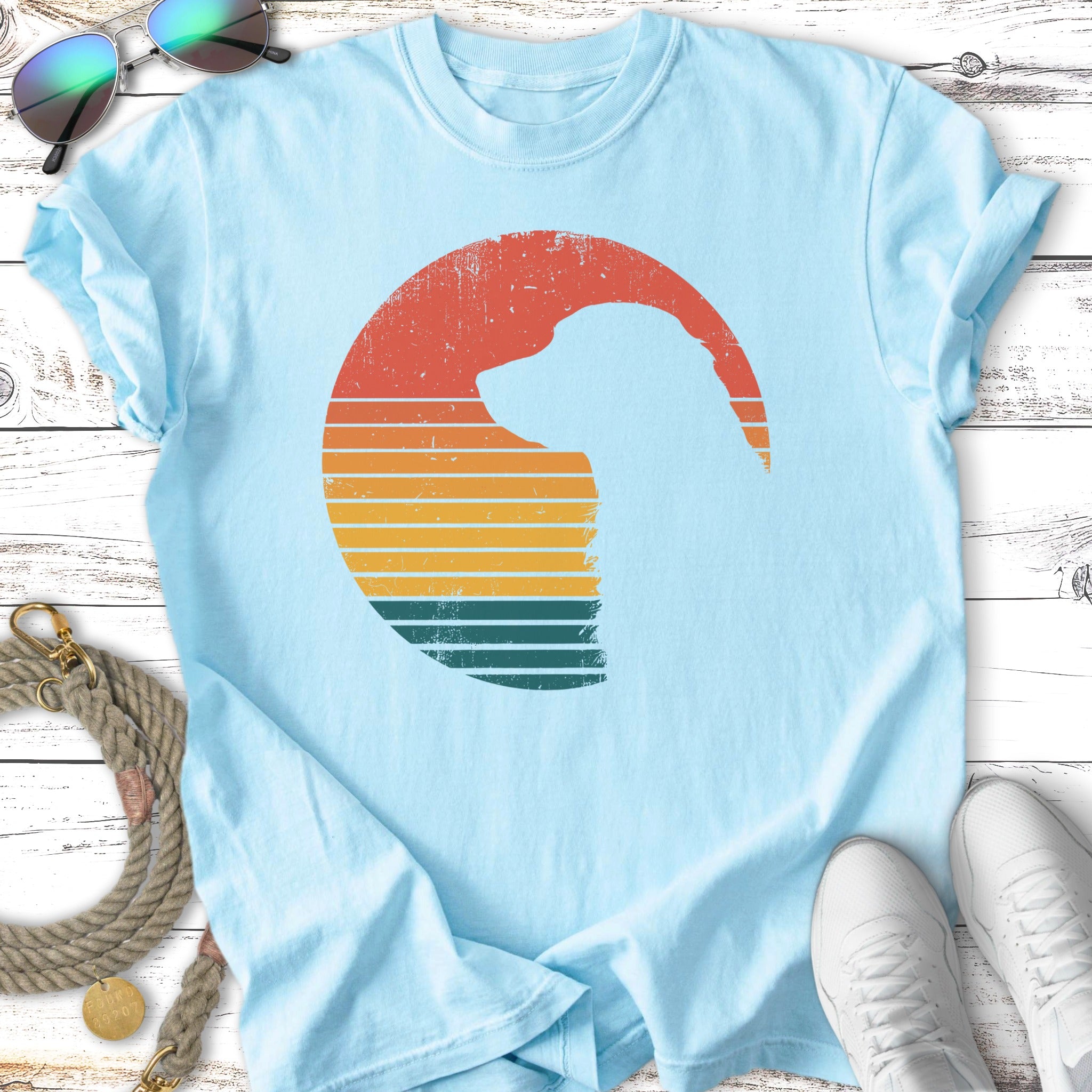 Light blue t-shirt with a silhouette of a dog's head within a retro sunset graphic.