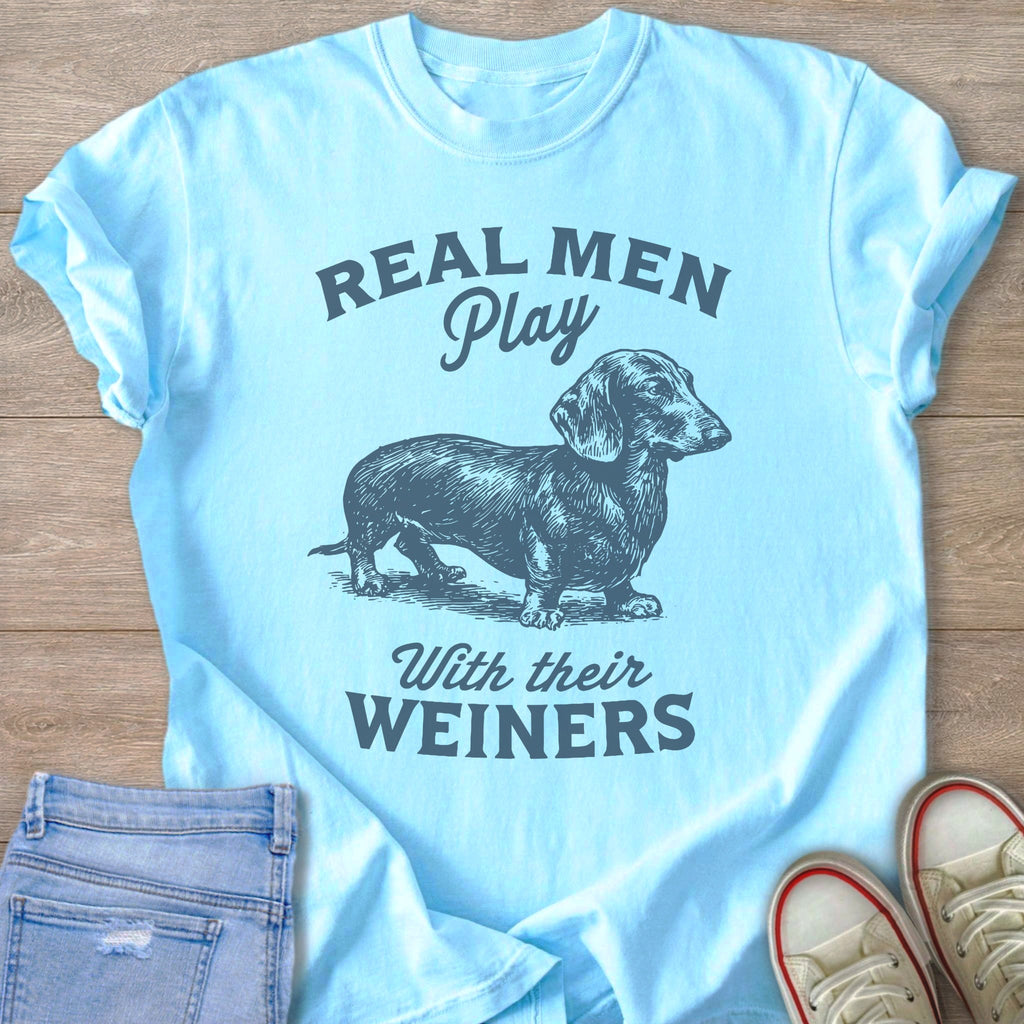 Light blue t-shirt with text "REAL MEN Play With their WEINERS" and dachshund graphic.