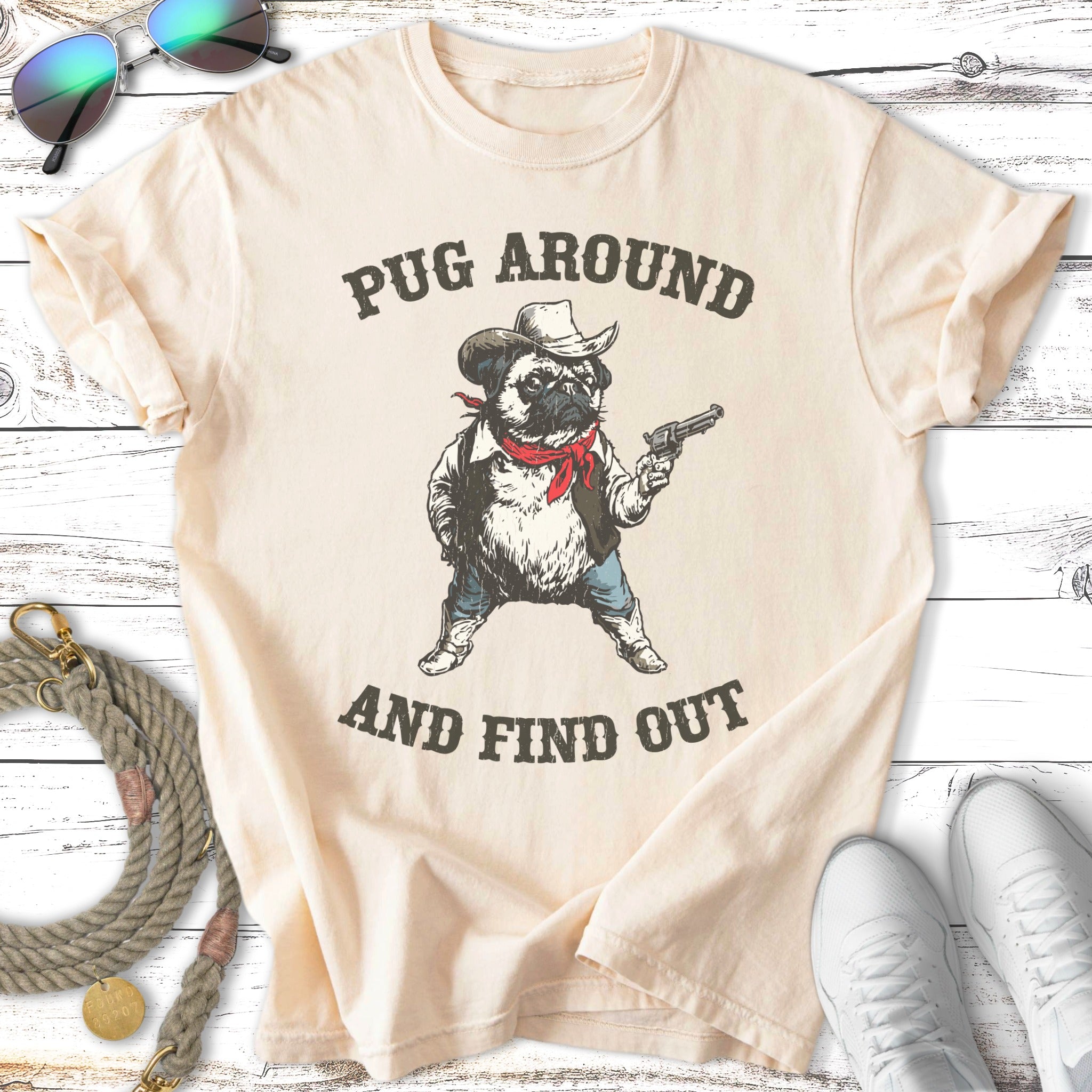 Pug wearing cowboy hat and bandana holding a gun, with text "Pug Around And Find Out".