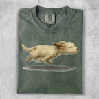Green t-shirt with a painting of a fluffy white dog jumping.
