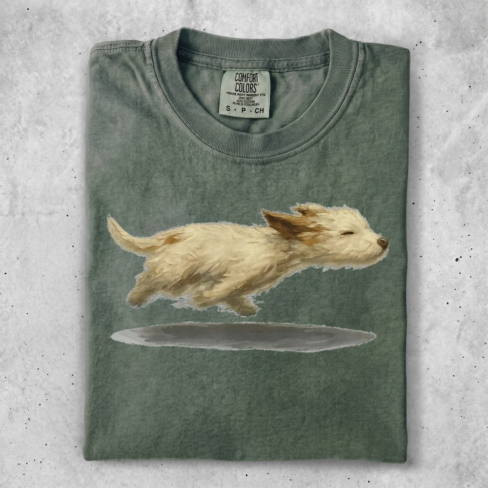 Green t-shirt with a painting of a fluffy white dog jumping.