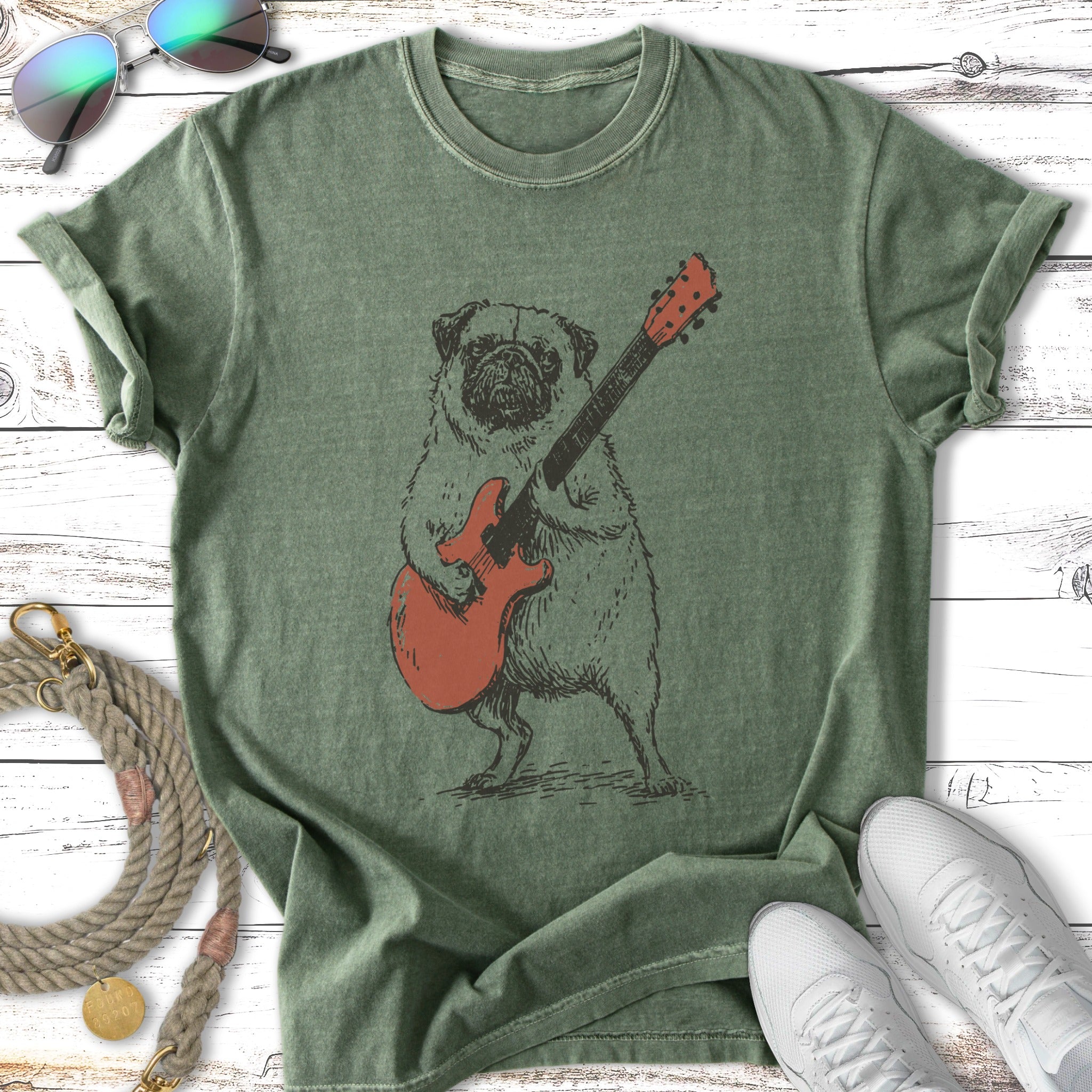 Sketch of a pug playing an orange electric guitar on a green t-shirt.