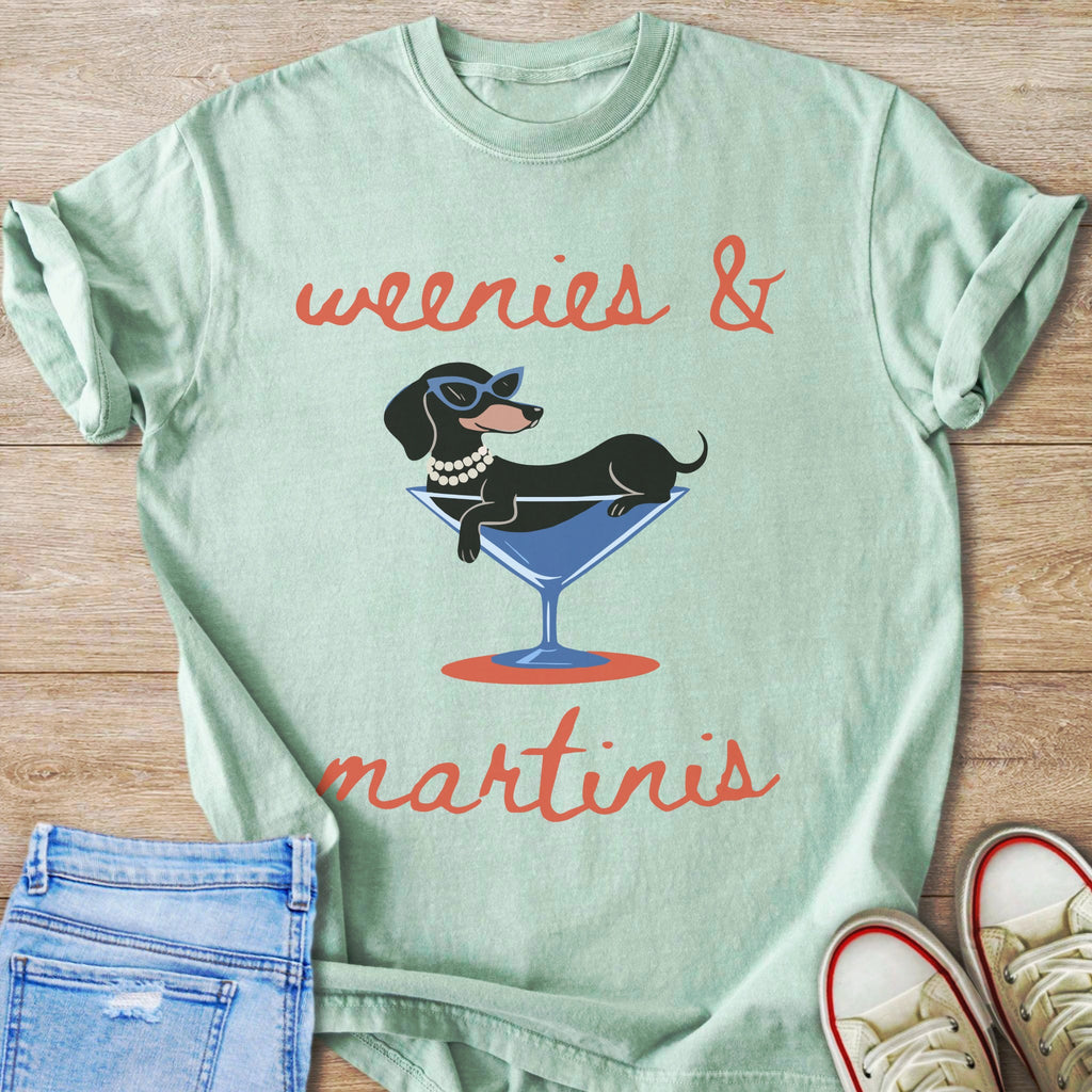 Light green t-shirt with graphic of dog in martini glass, text "weenies & martinis".