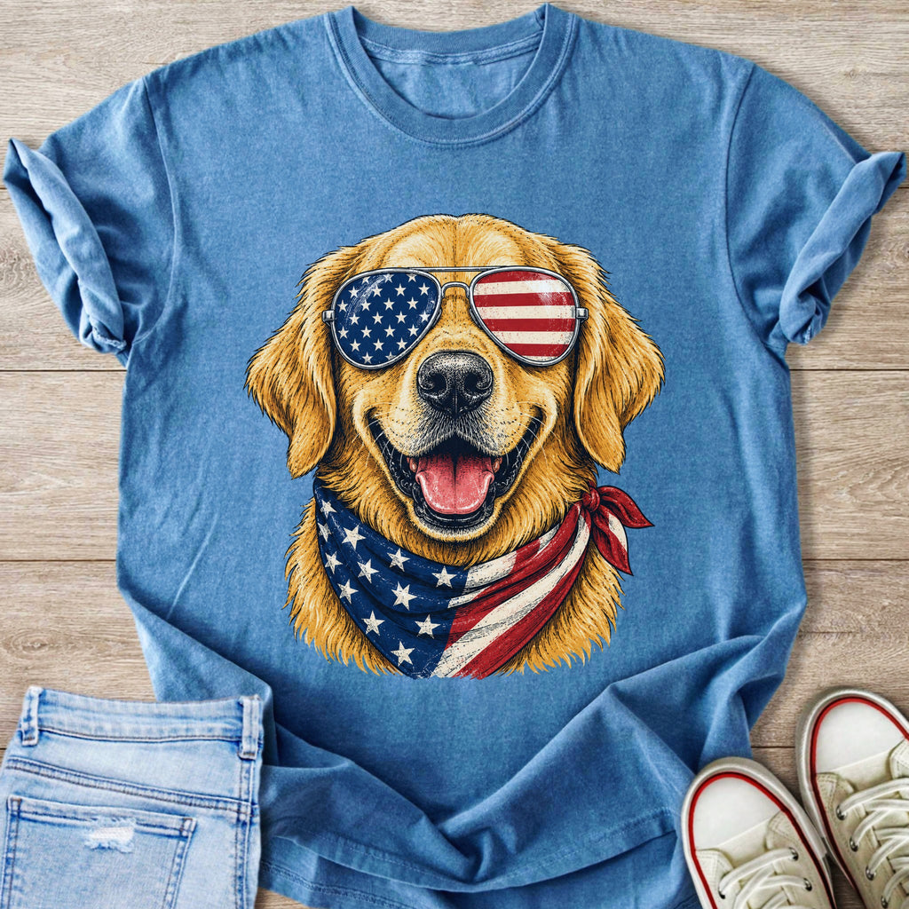 Golden retriever wearing American flag sunglasses and bandana on a blue t-shirt.