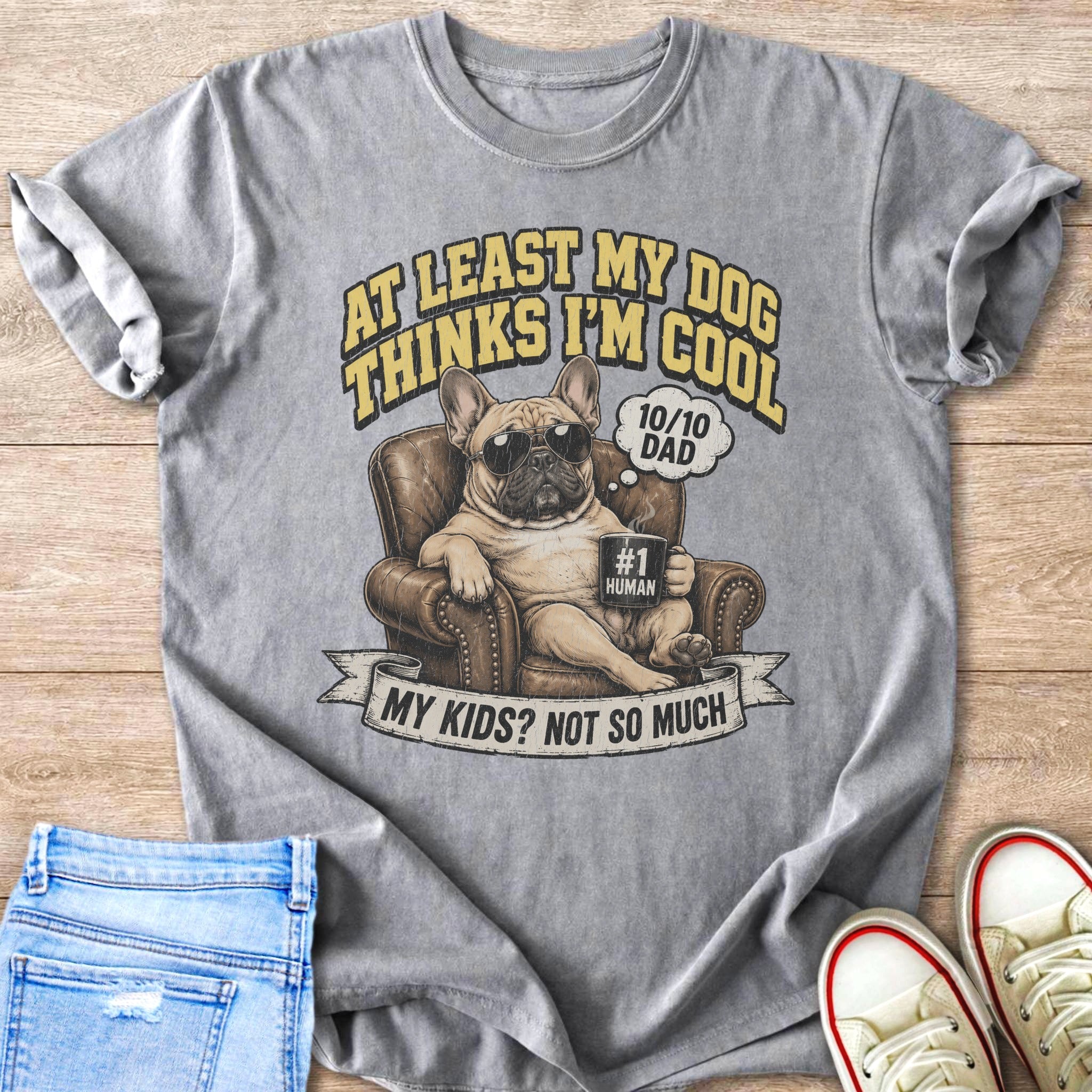 French bulldog wearing sunglasses sitting in a chair, text says "At Least My Dog Thinks I'm Cool".