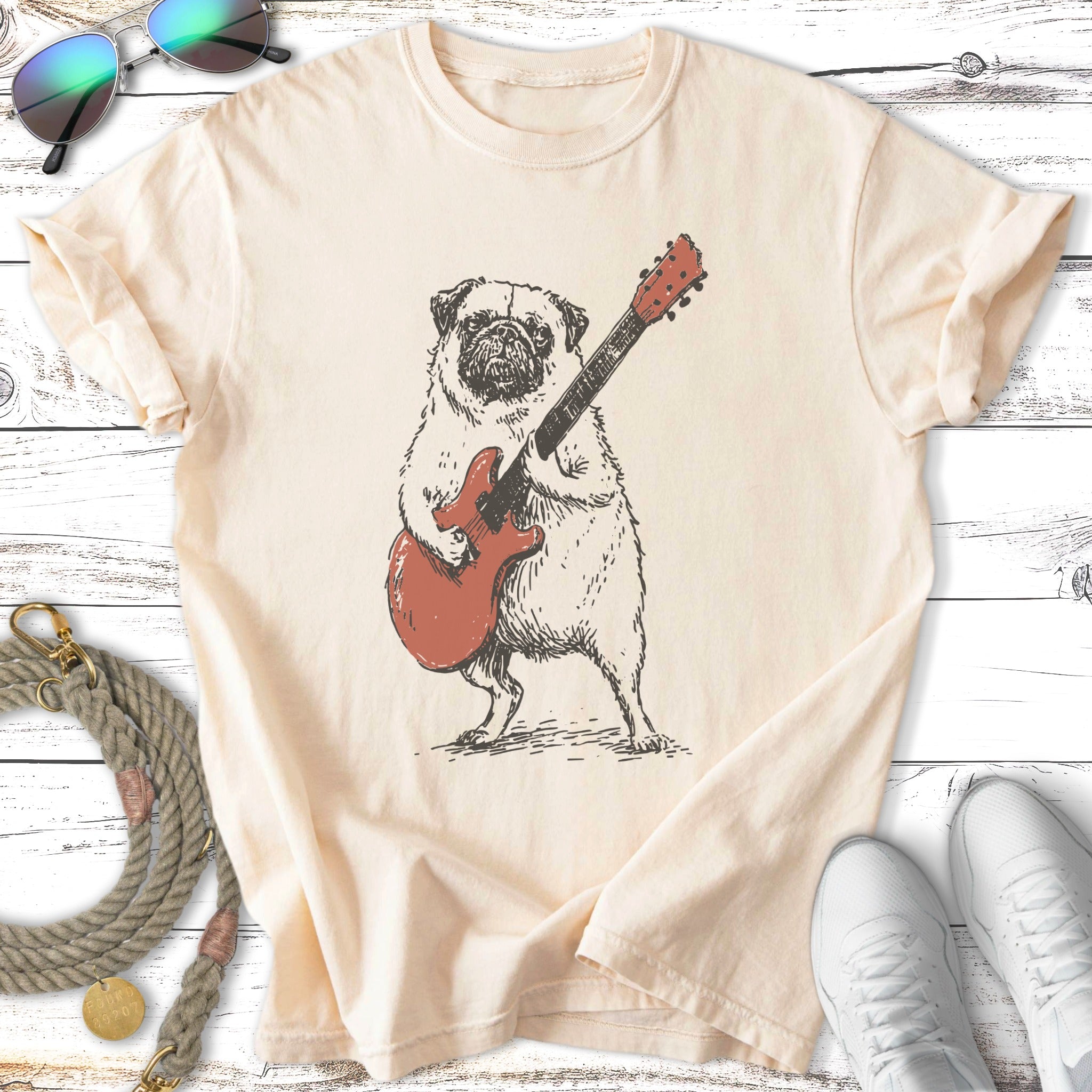 Pug wearing a shirt and playing a red electric guitar.
