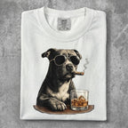 Dog wearing sunglasses and smoking a cigar with a glass of whiskey.