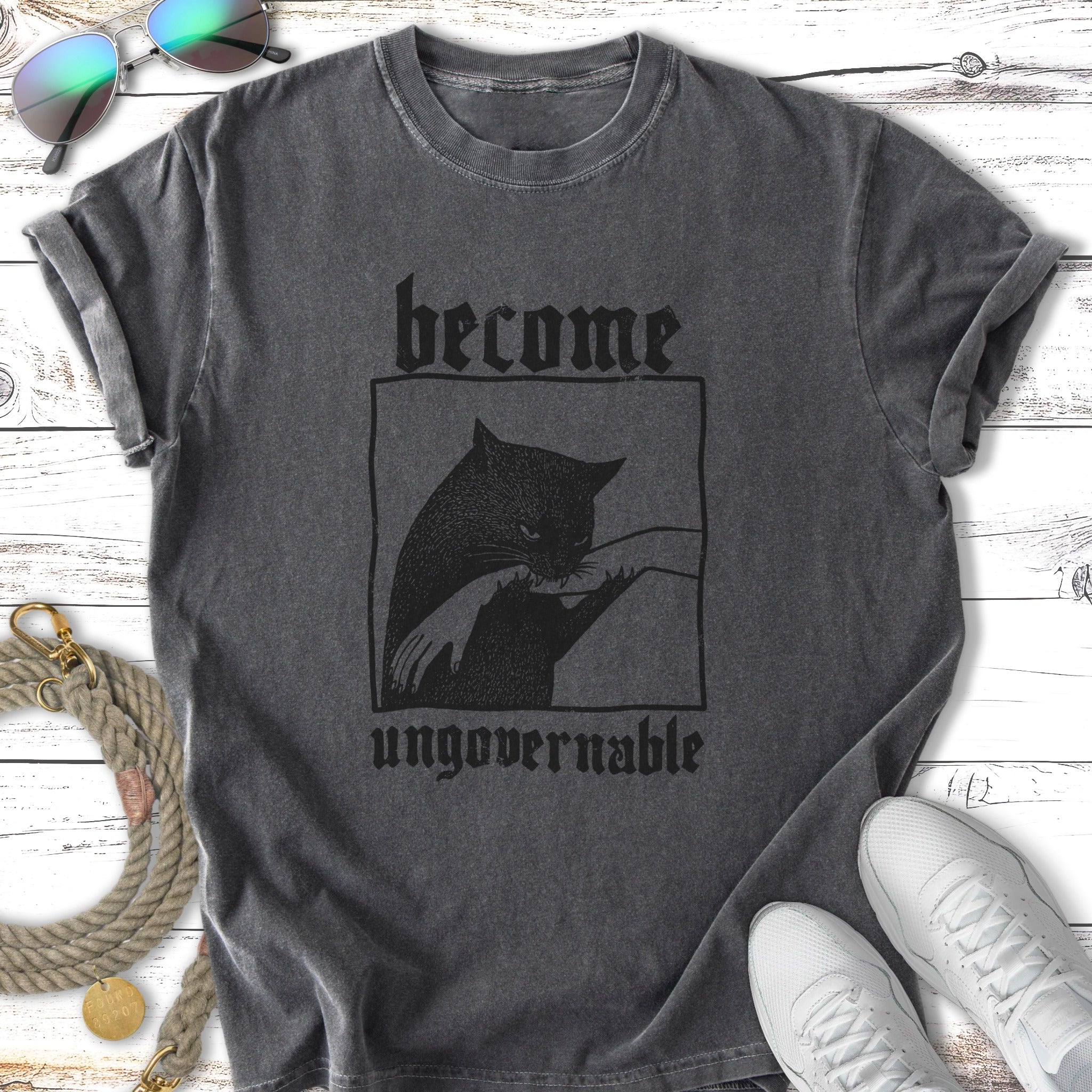 Black cat biting hand with text "become ungovernable" on a t-shirt.