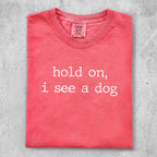 Coral t-shirt with "hold on, i see a dog" printed in white text.