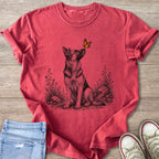 German Shepherd looking up at a monarch butterfly on a red t-shirt.