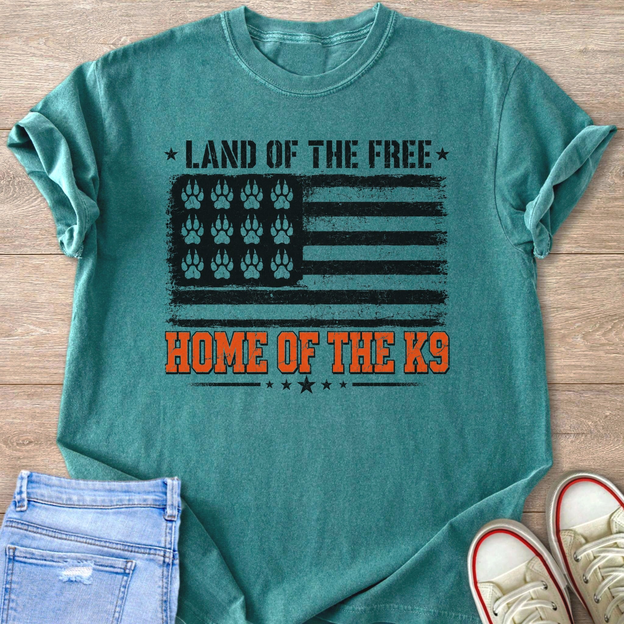 Teal t-shirt with distressed American flag graphic featuring paw prints and "Land of the Free Home of the K9".