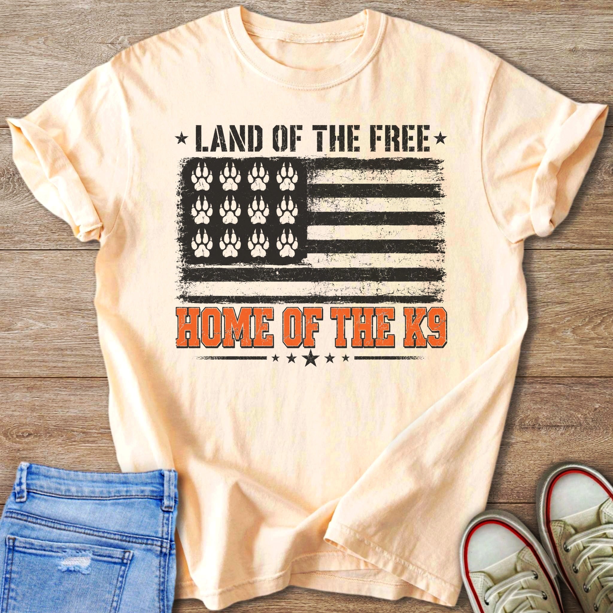 Peach t-shirt with American flag design featuring paw prints and text.