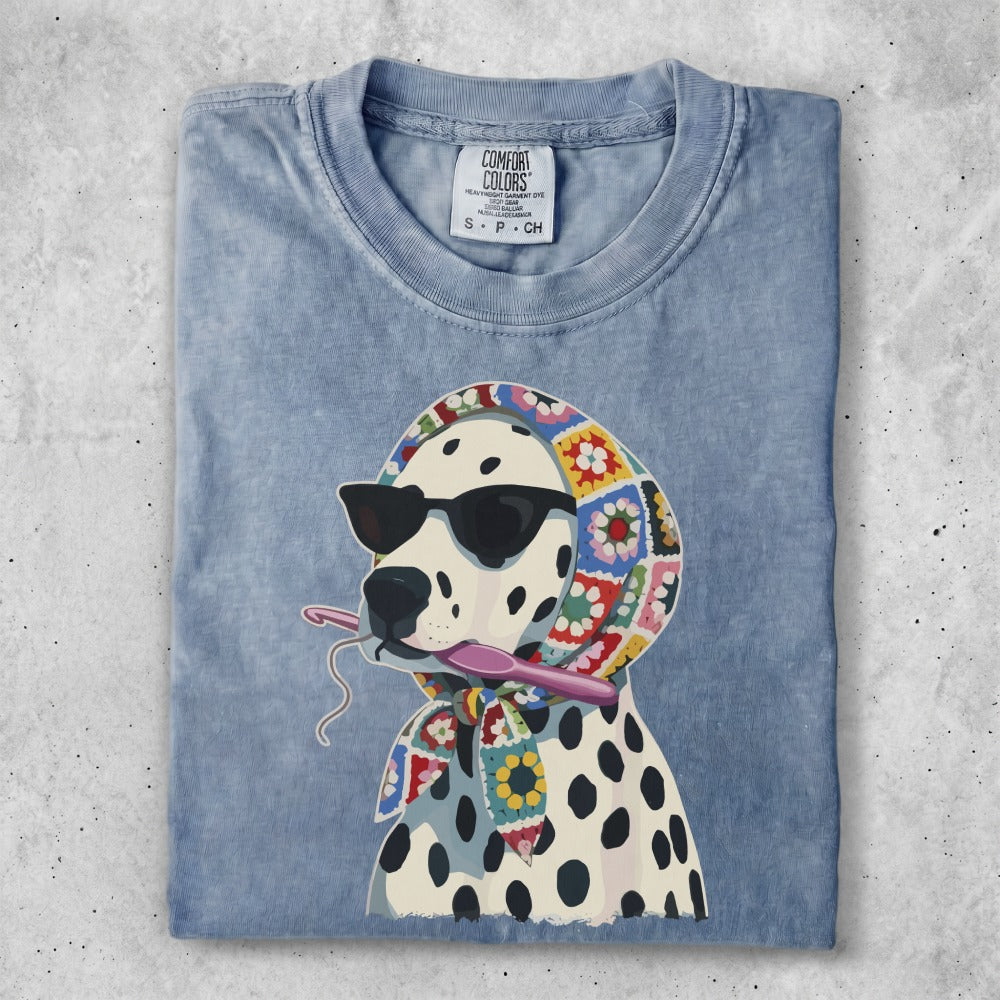 Dalmatian wearing sunglasses and a crochet scarf, holding yarn and a crochet hook.