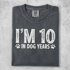 "I'm 10 in dog years" graphic tee on a dark grey shirt.