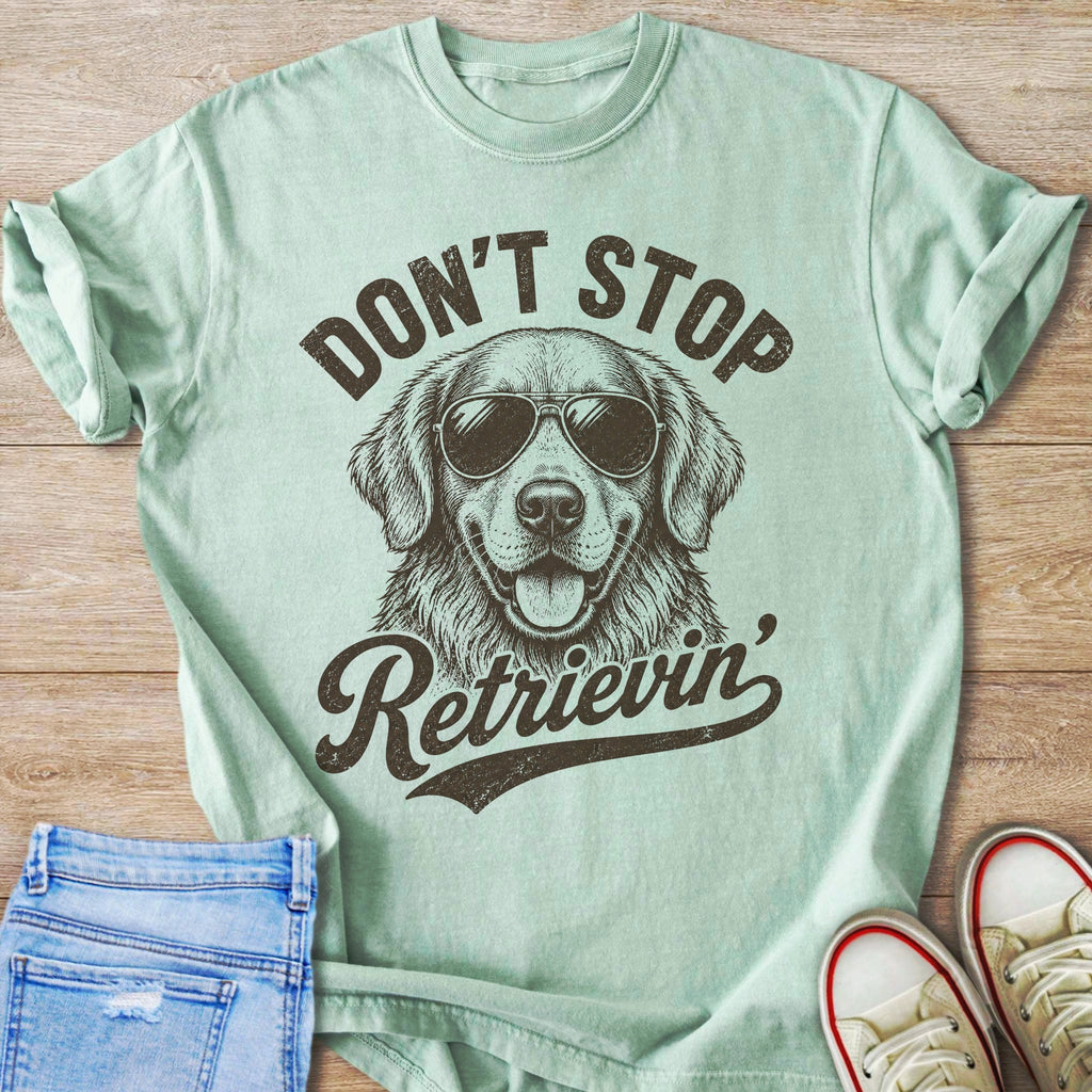 Light green t-shirt with a drawing of a golden retriever wearing sunglasses and text.