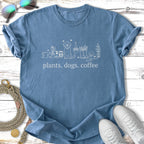 Blue t-shirt with "plants. dogs. coffee" text and line art of plants and dogs.