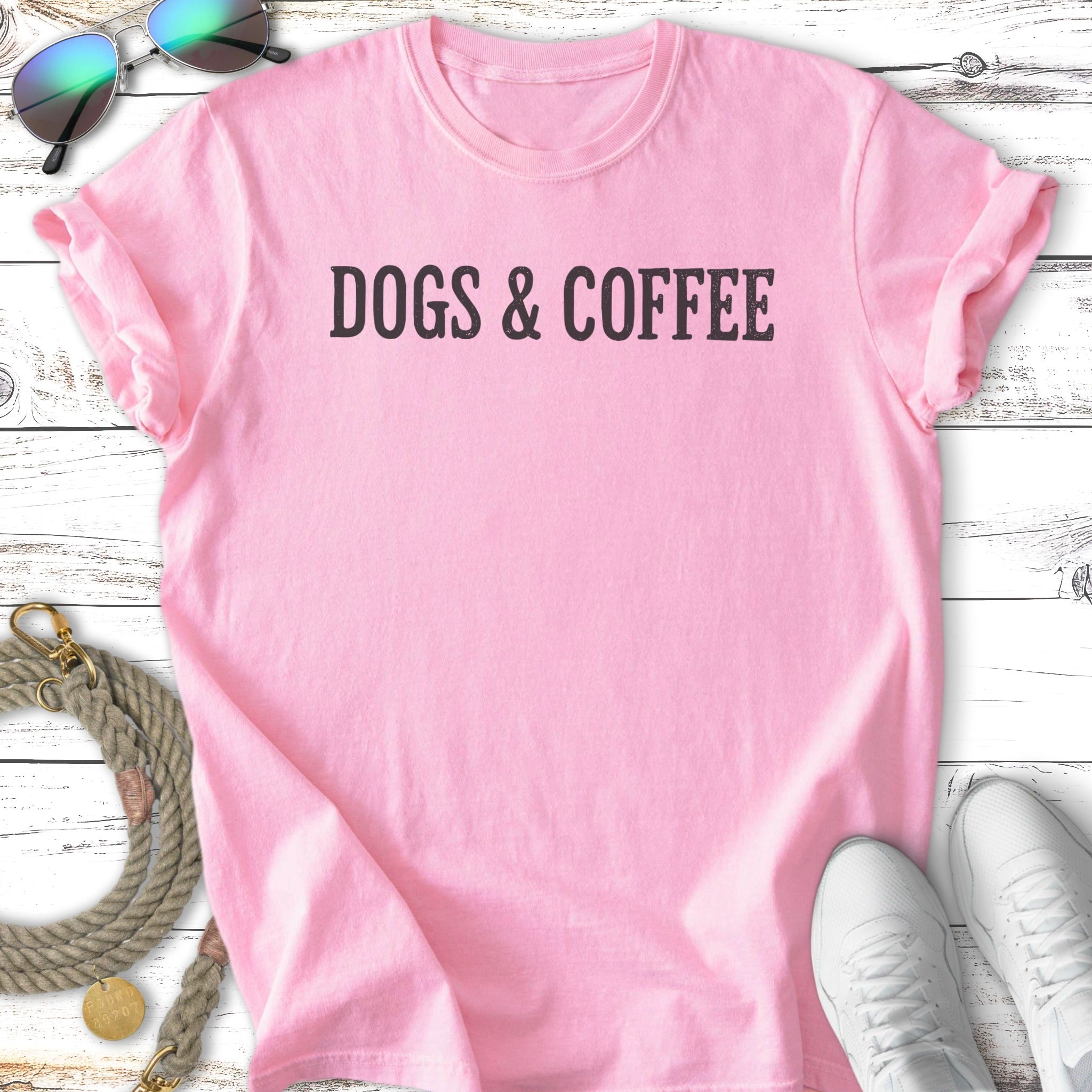 Pink t-shirt with "DOGS & COFFEE" text, dog leash, and sneakers.