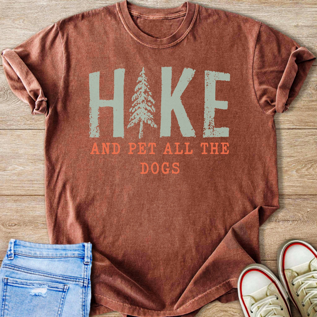 Rust colored t-shirt with "Hike and pet all the dogs" graphic.