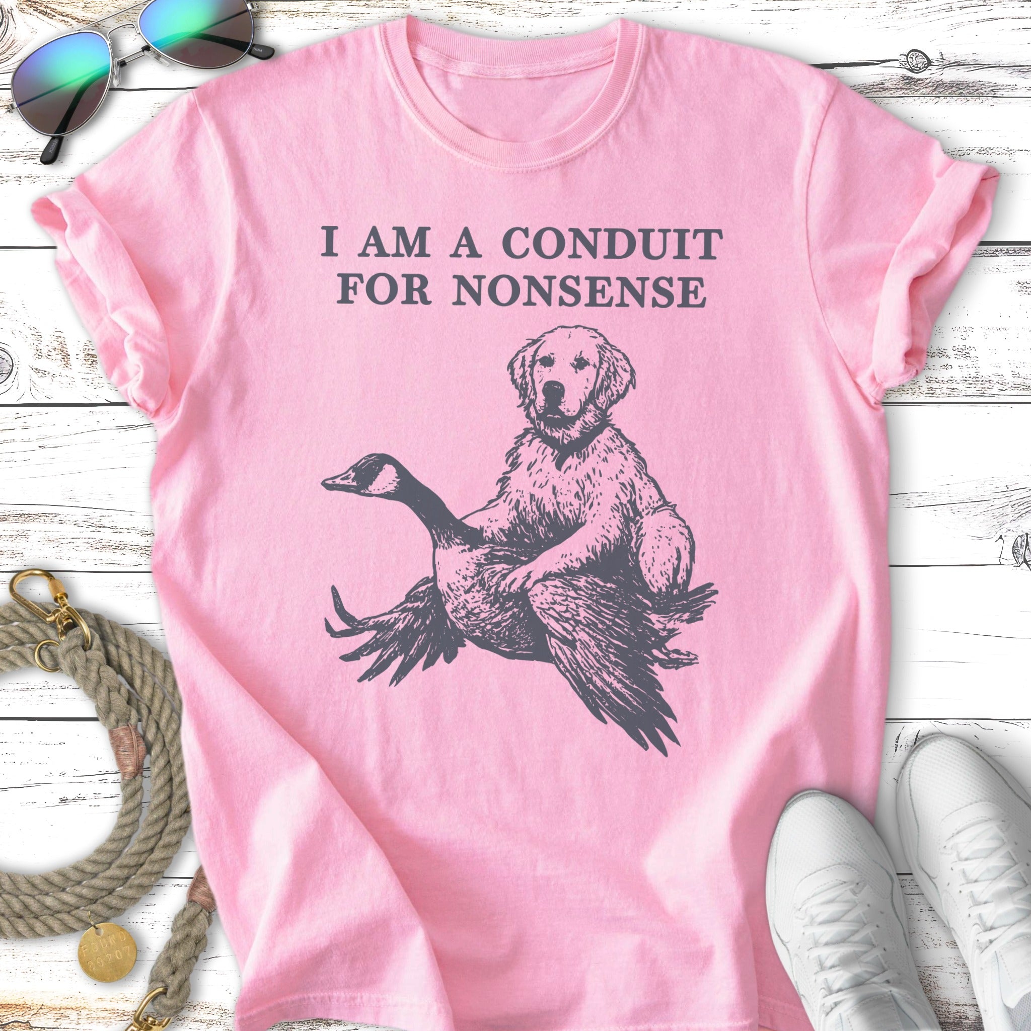 Pink t-shirt with a dog riding a goose, text reads "I AM A CONDUIT FOR NONSENSE".