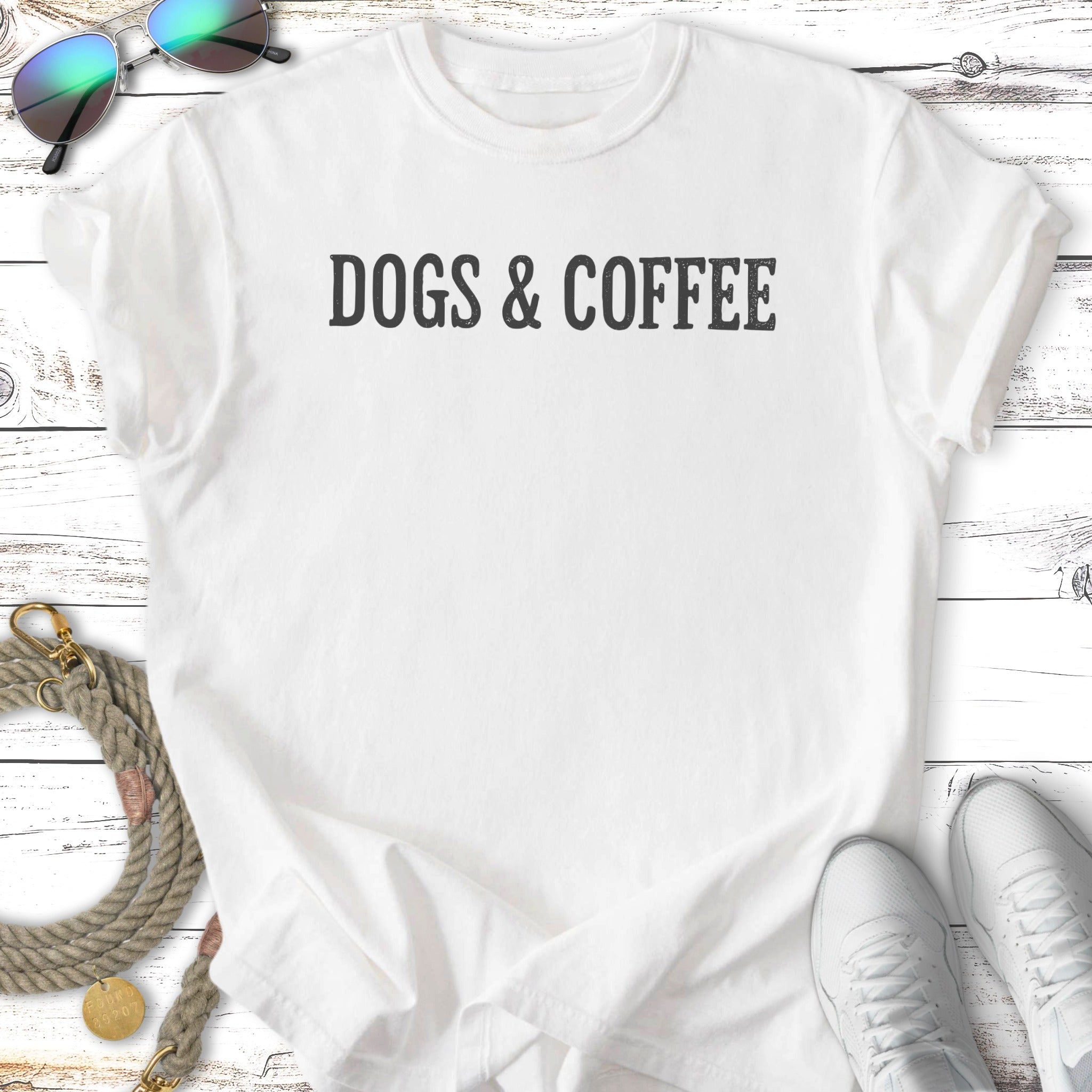 White t-shirt with "DOGS & COFFEE" text, styled with sunglasses, leash, and sneakers.