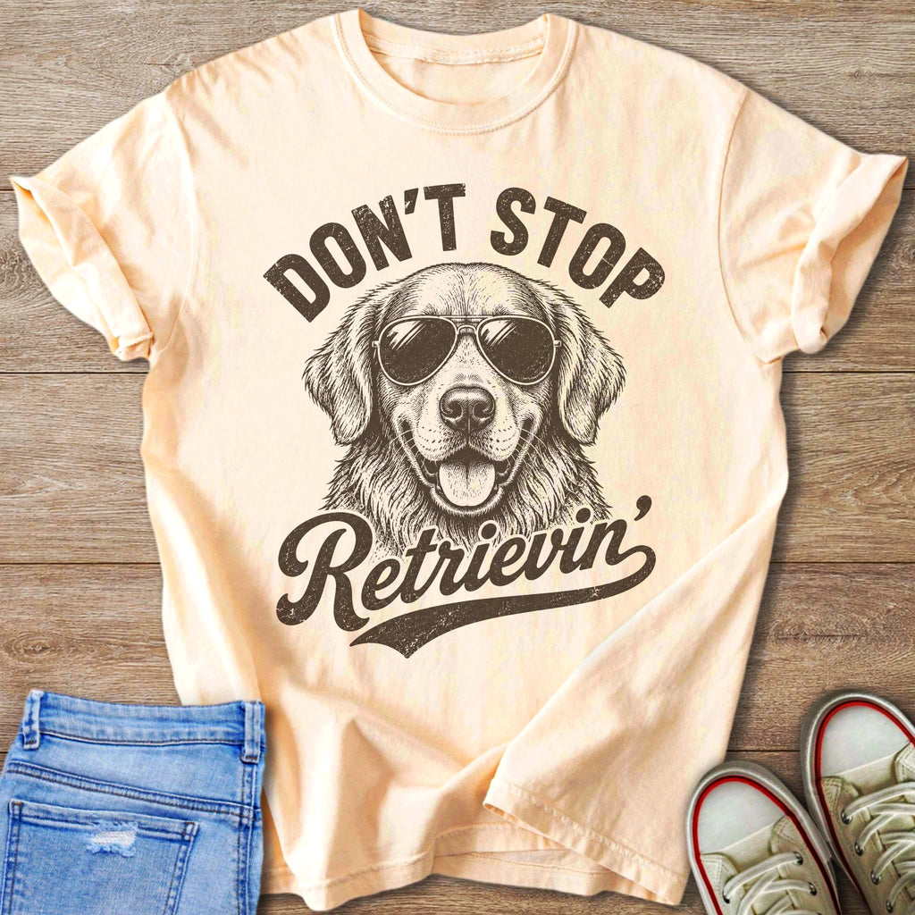 Peach t-shirt with graphic of dog wearing sunglasses and text "Don't Stop Retrieving."