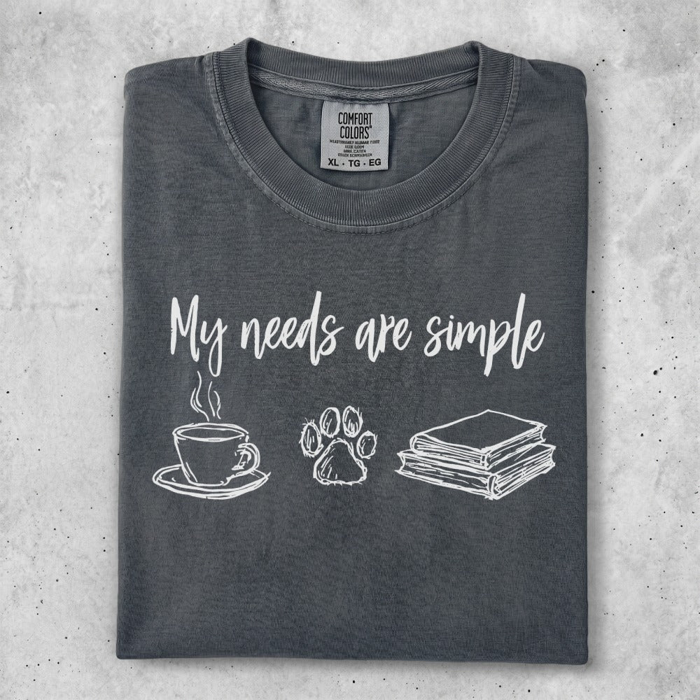 Gray t-shirt with "My needs are simple" and icons for coffee, paw print, and books.