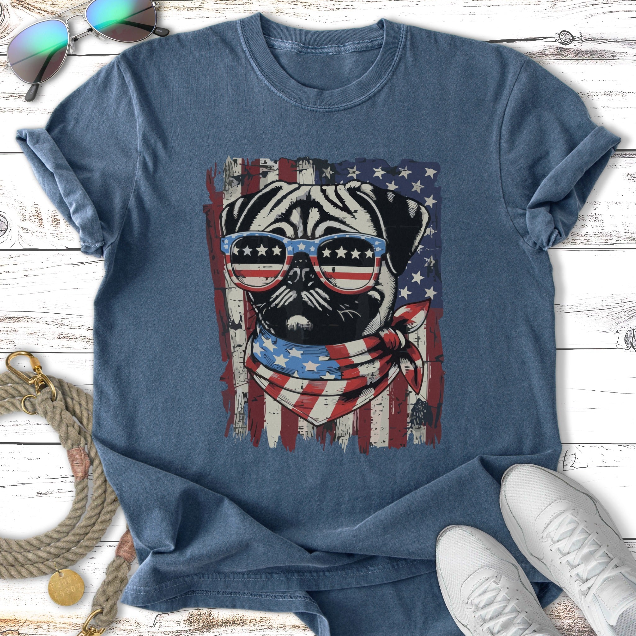 Pug wearing sunglasses and bandana in front of American flag.