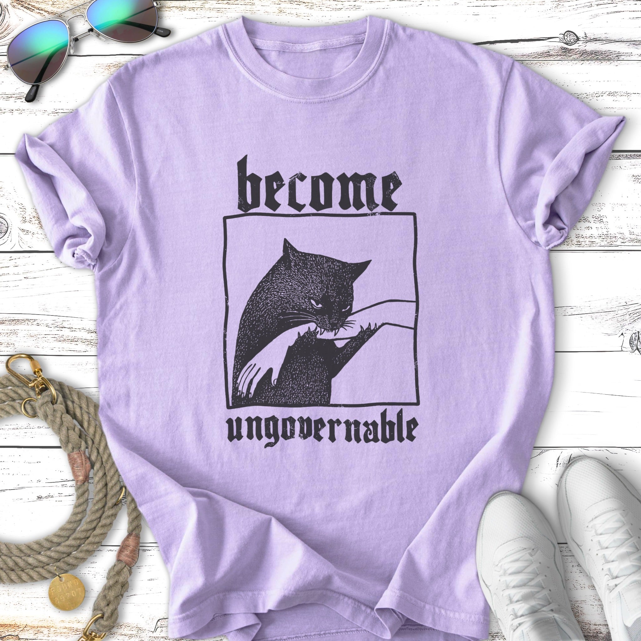 Purple t-shirt with black illustration of a cat and text "become ungovernable".
