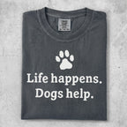 Dark gray t-shirt with white text "Life happens. Dogs help." and a paw print.