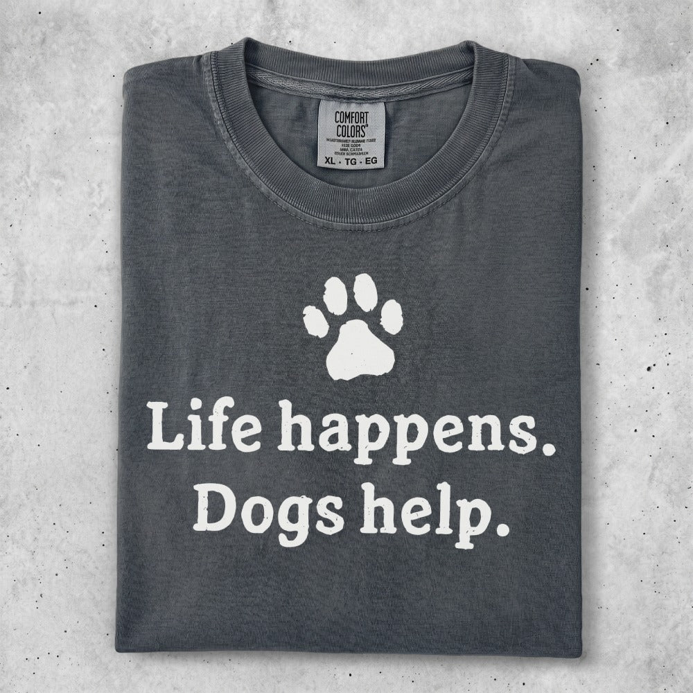 Dark gray t-shirt with white text "Life happens. Dogs help." and a paw print.