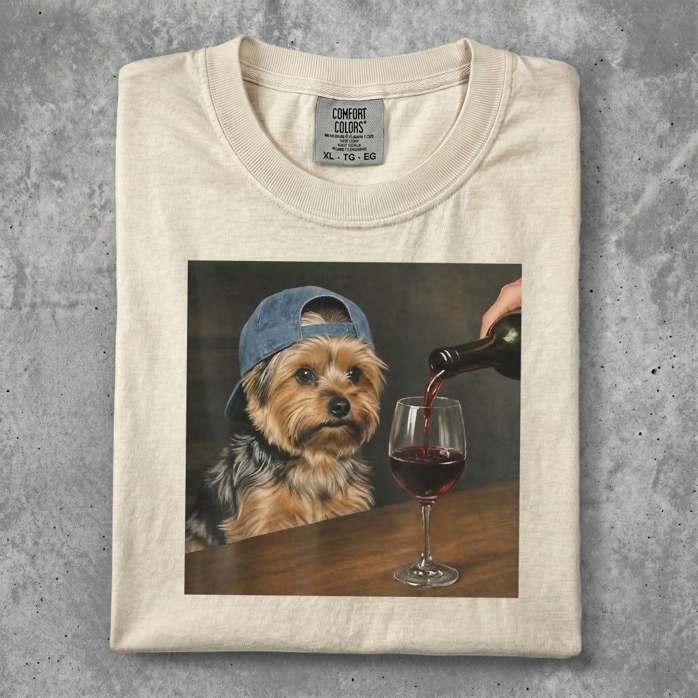 Yorkshire terrier wearing a blue cap being poured red wine into a glass.