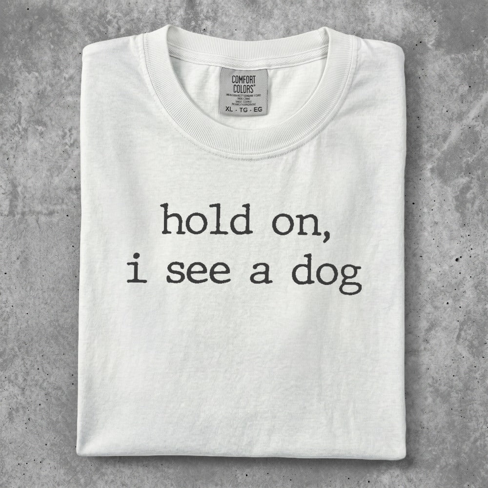White t-shirt with "hold on, i see a dog" text.