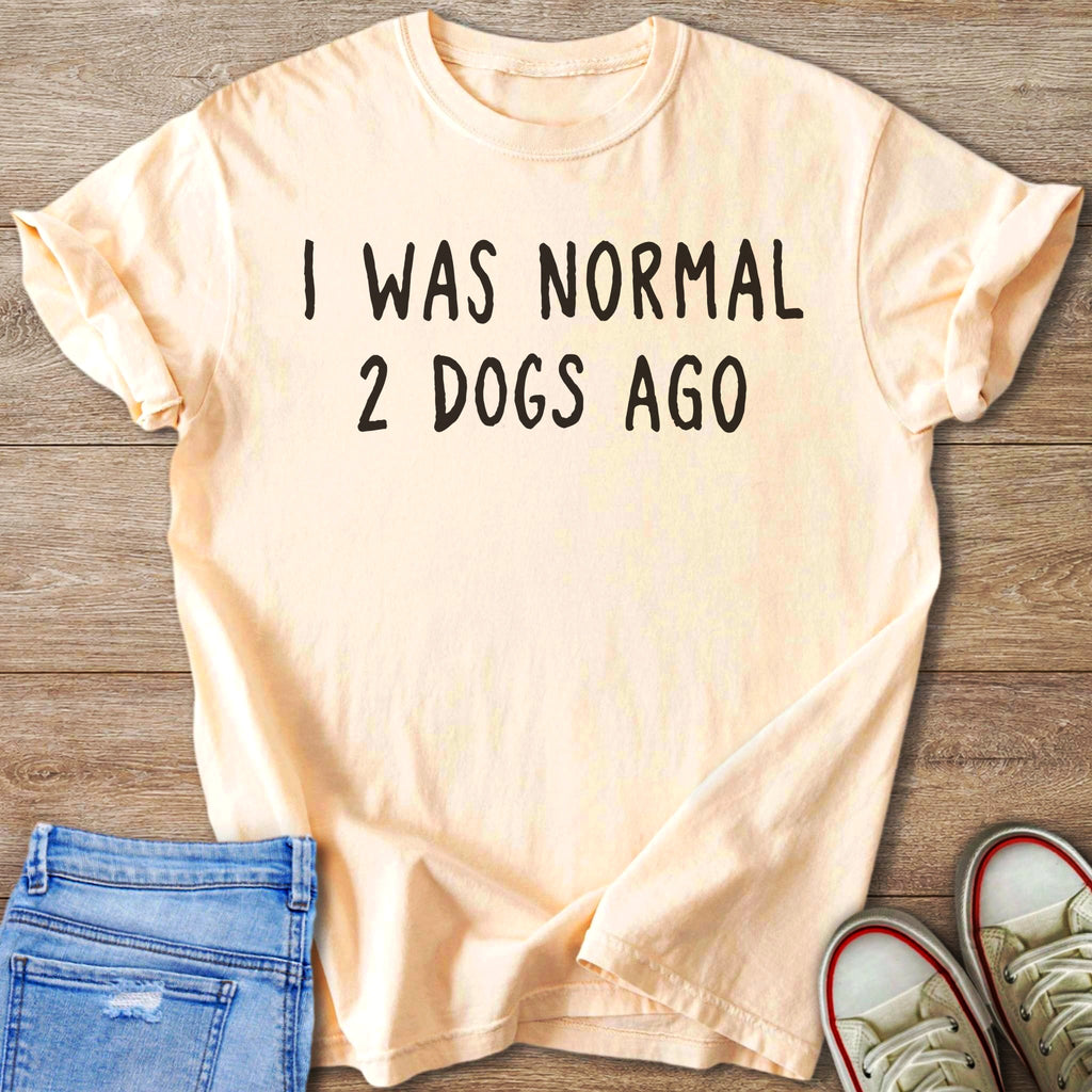 Peach t-shirt with black text that reads "I WAS NORMAL 2 DOGS AGO".