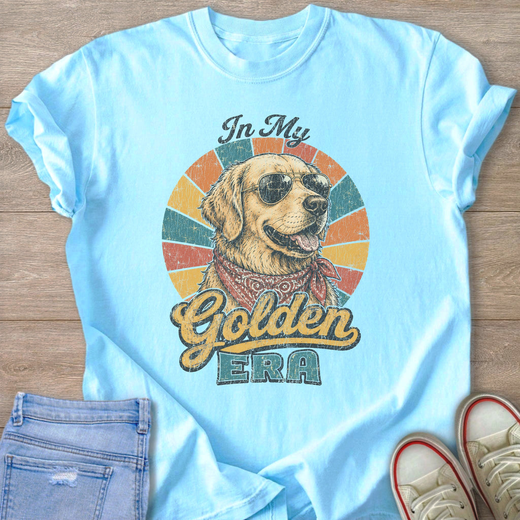 Light blue t-shirt with a graphic of a golden retriever wearing sunglasses and a bandana, with text "In My Golden ERA".