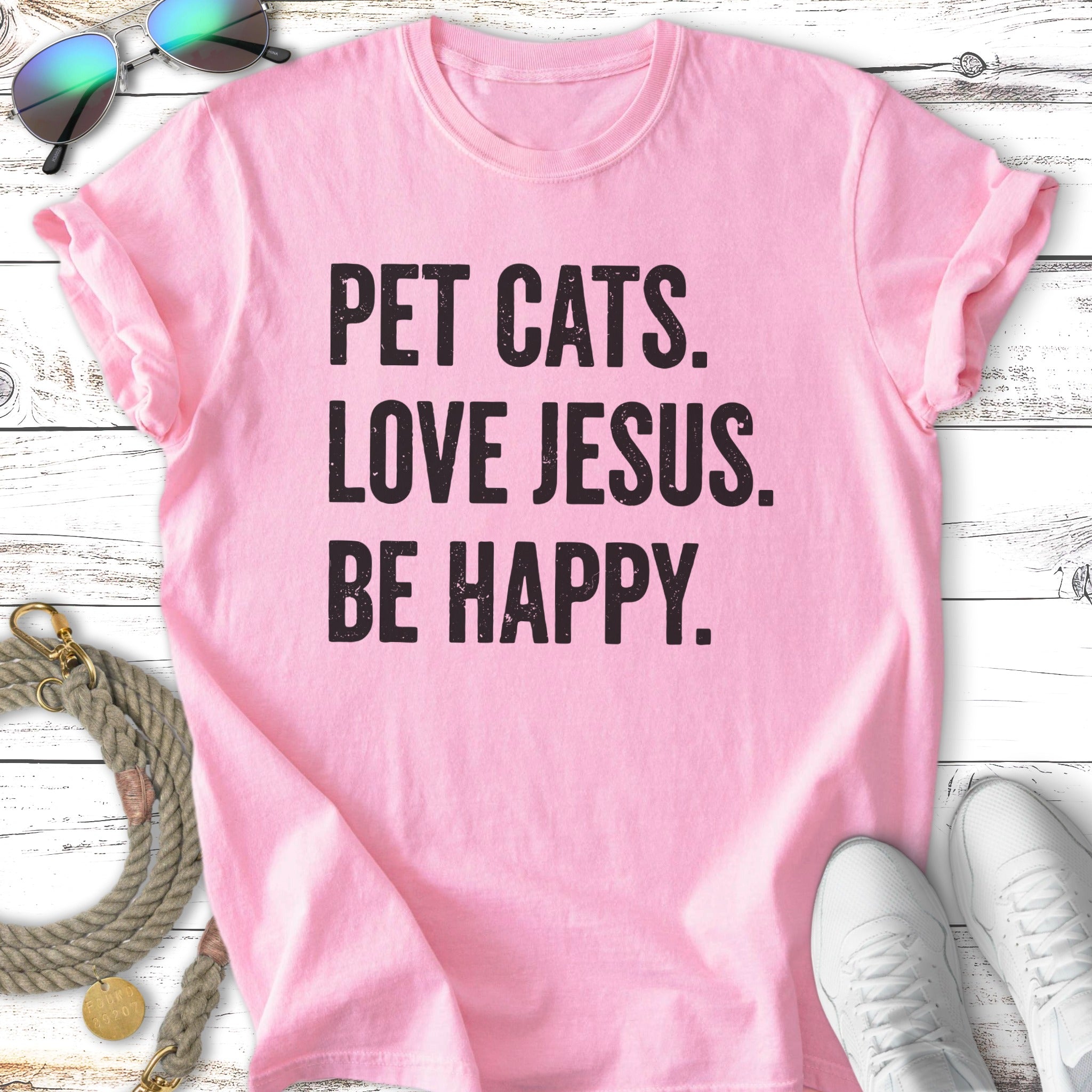 Pink t-shirt with "Pet Cats. Love Jesus. Be Happy." text.