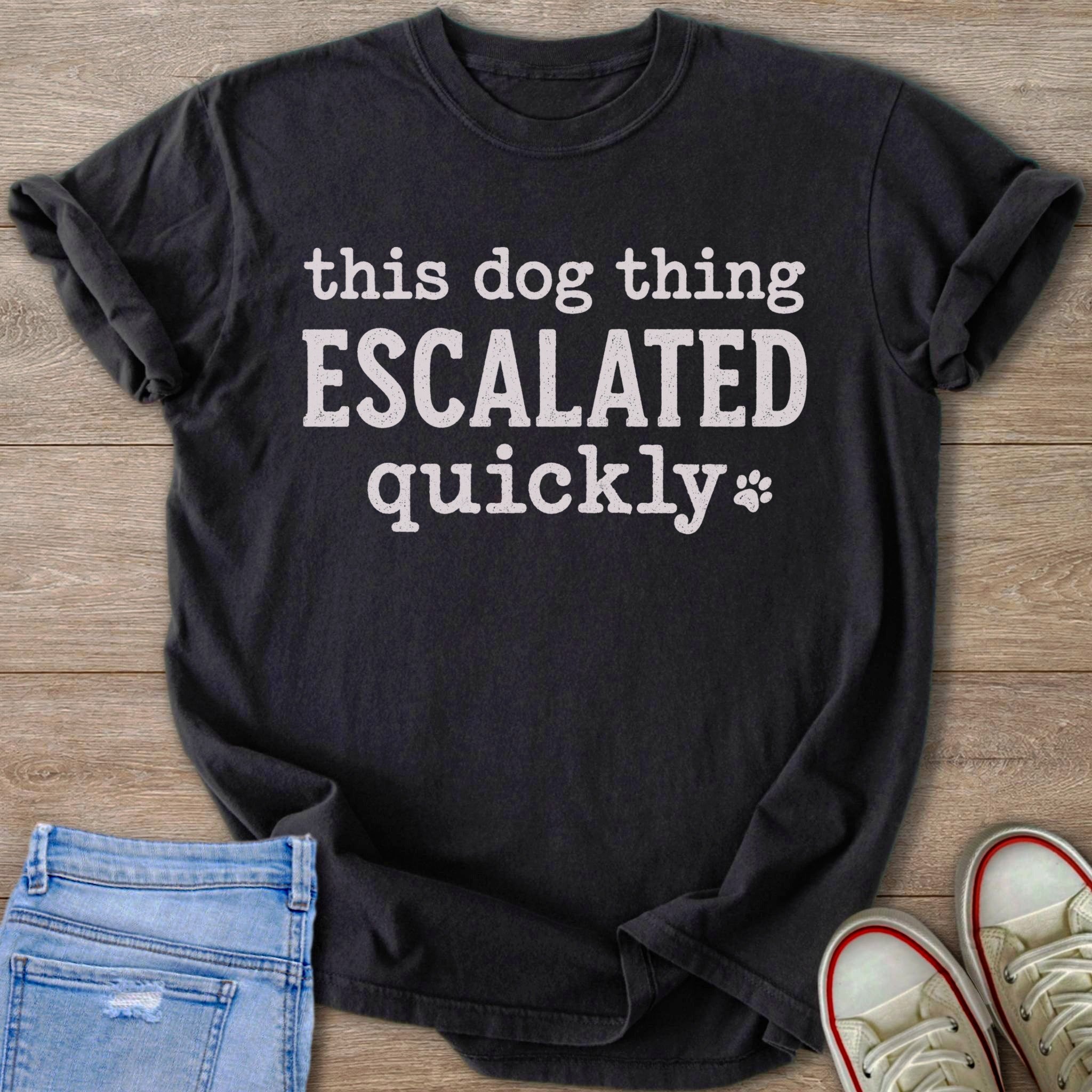 Dark t-shirt with white text "this dog thing ESCALATED quickly" and a paw print.