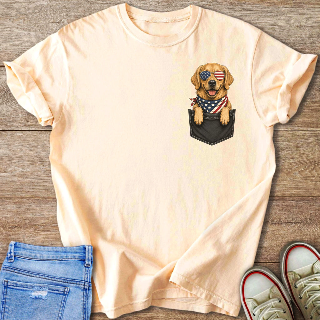 Peach t-shirt with graphic of golden retriever in a pocket wearing American flag sunglasses and bandana.