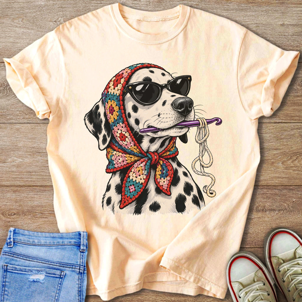 Dalmatian dog wearing sunglasses and a crochet scarf holds yarn and crochet hook.
