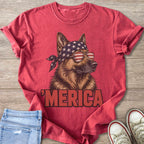 German Shepherd wearing American flag bandana and sunglasses with "MERICA" text.