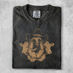 Dark t-shirt with a sketched brown dog in a cowboy hat, smoking a cigar, flanked by cows.