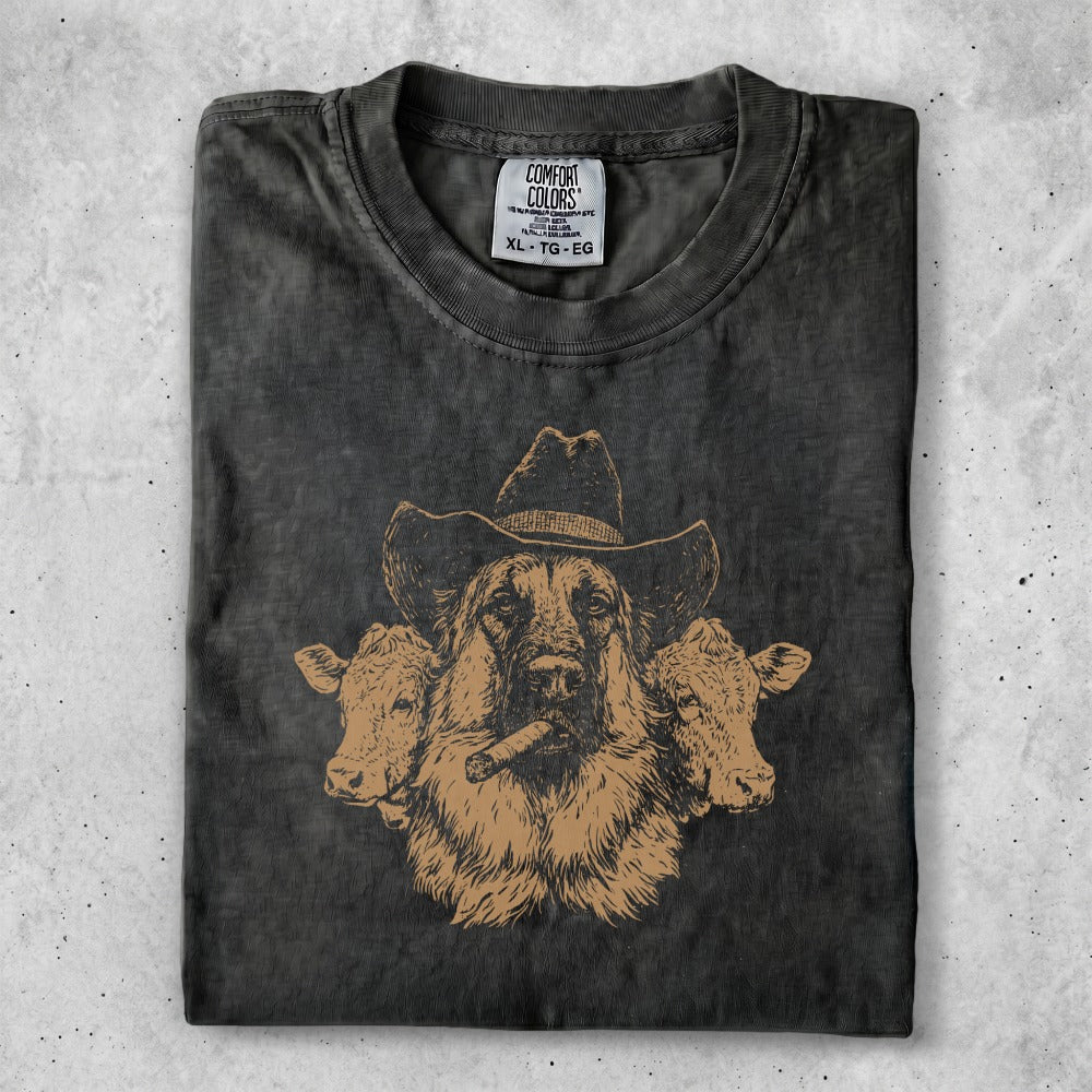 Dark t-shirt with a sketched brown dog in a cowboy hat, smoking a cigar, flanked by cows.