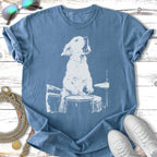 Golden retriever puppy playing a drum set, white outline on a blue t-shirt.