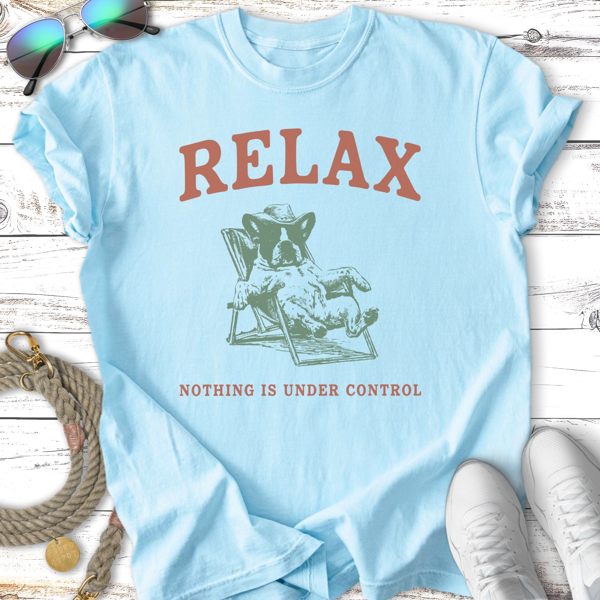 Light blue t-shirt with graphic of dog relaxing and text "RELAX NOTHING IS UNDER CONTROL".