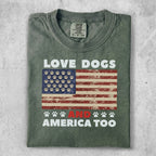 Green t-shirt with American flag, paw prints, and text "LOVE DOGS AND AMERICA TOO".
