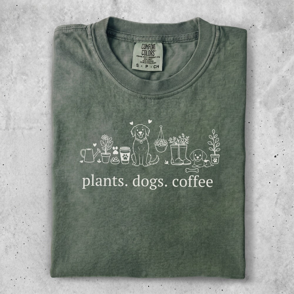 Green t-shirt with "plants. dogs. coffee." text and line-art illustrations.